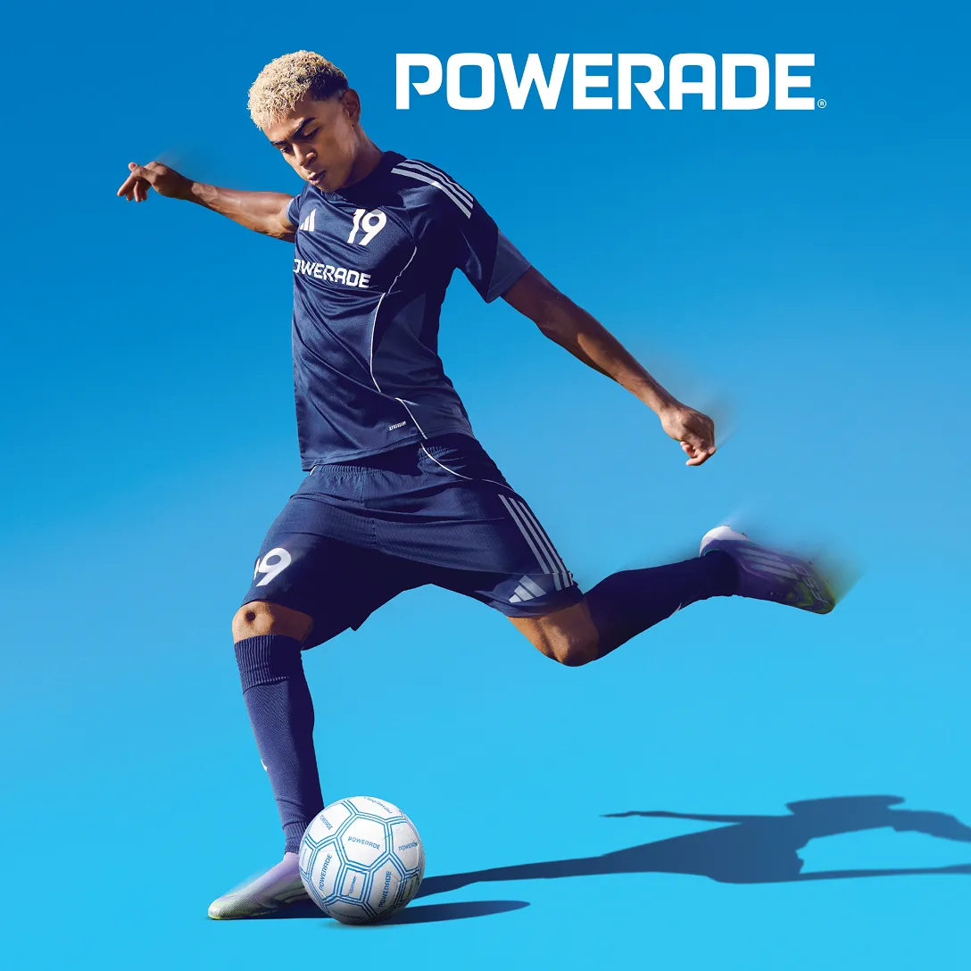 A soccer player kicking a ball on a blue background